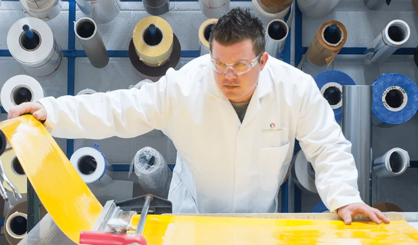 A man in a lab examining high quality medical labels on a yellow sheet of paper.