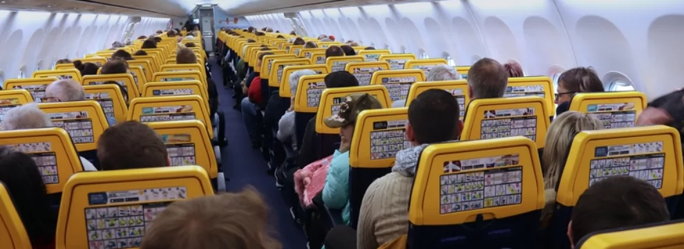 People sitting in an airplane with yellow seats and medical labels.