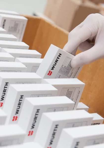 A person in a white glove is putting boxes into a box.