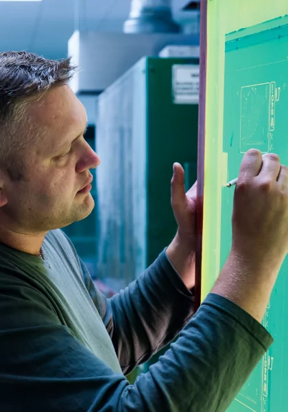 A man is drawing high quality medical labels on a green screen.
