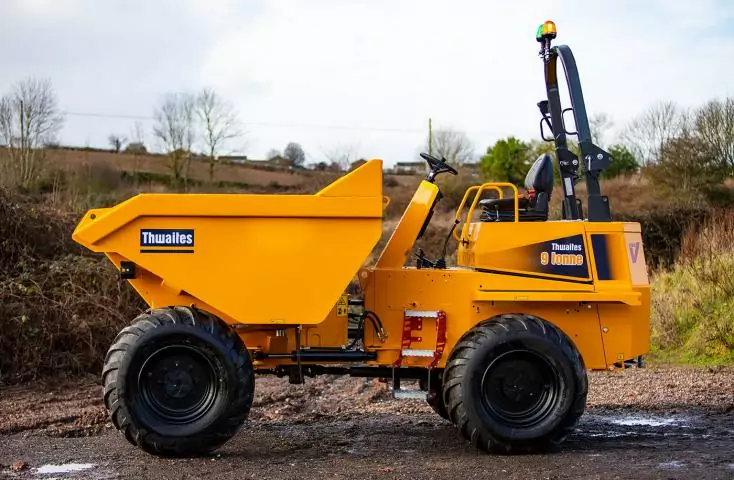 A custom yellow dump truck is parked on a dirt road.