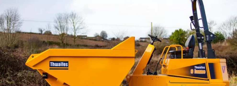 A yellow excavator with high quality labels is parked in a field.